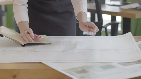 A female architect is studying a building plan in the design office. Video stock 132986243