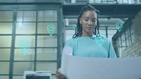 Female architect unrolling blueprint in loft workspace as teal pins appearing Stock Footage 333494700
