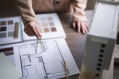 Female architect using divider compass to drawing building project and desi.. Stock Photos
