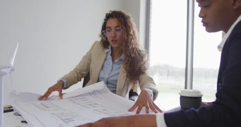 Female architects talking and checking architects plans in modern office Stock Footage 342797799