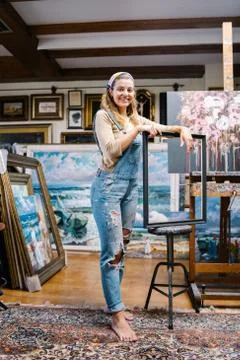 Female artisan with frame standing in art workshop Stock Photos