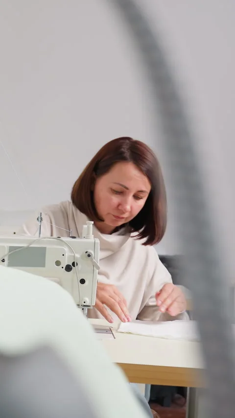 Female artisan multitasking between sewing machine and design pattern, Woman Stock Footage 330799727
