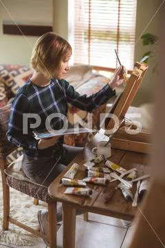 Female artist painting picture on canvas in living room Stock Photos