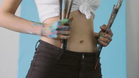 Female artist playing with tools in studio, she soiled with multicolored paint Stock Footage 158631310