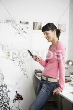 Female Artist Text Messaging On Cell Phone Stock Photos