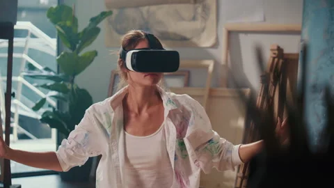 A Female Artist Using VR Headset to Paint in His Bright Studio Surrounded by Stock Footage 307649987