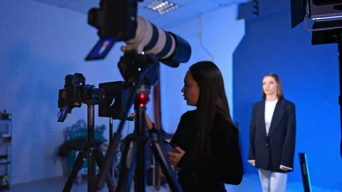 Female assistant checking video camera setup during professional studio shoot. Video stock 329192548