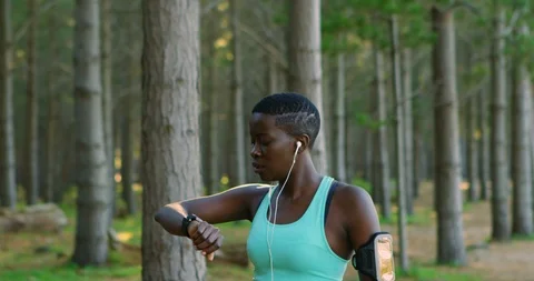 Female athlete checking time while jogging in forest 4k Stock Footage 94207310