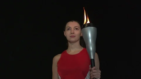Female Athlete Holding the Olympic Torch. Black Background. Rotating Stock Footage
