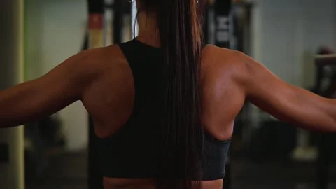 A female athlete performs upper body exercises in a gym. The focus is on Stock Footage 345026756