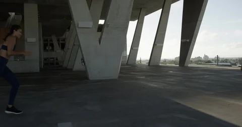 Female athlete running on top of an empty parking garage Stock Footage 99316342