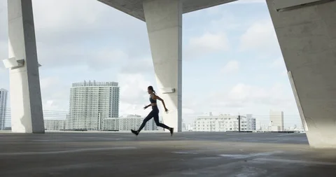 Female athlete running on top of an empty parking garage Stock Footage 99316534