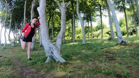 Female athlete stretches before going for a run in the forest Stock Footage 98131853