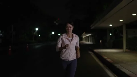Female athlete in training  jogging through the streets at night Stock Footage 150209032