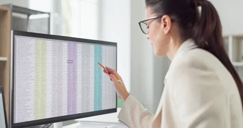 Female auditor pointing at spreadsheet on widescreen monitor for financial Stock Footage 330128293