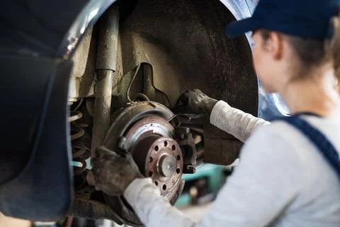 Female auto mechanic elevating car on car lift, checking breaks. Beautiful woman Stock Photos
