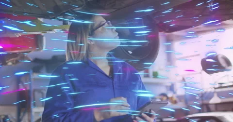 Female auto tech tapping tablet under lifted vehicle running AR scan to Stock Footage 314659708