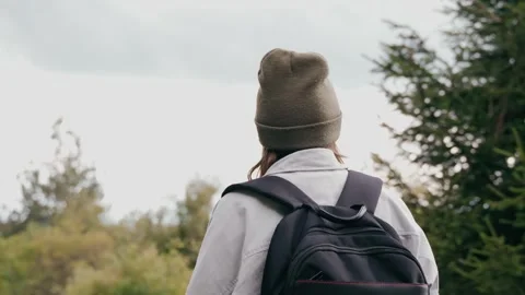 A female with a backpack walking along a forest road on a warm autumn day. Stock Footage 250317903