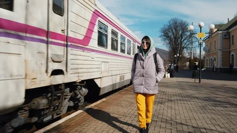 Female backpacker goes on the station platform, train arrives at the station Video stock 126010461