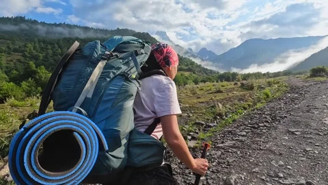 Female backpacker hikes uphill, side view, across a rocky trail in Svaneti Stock Footage 343774662