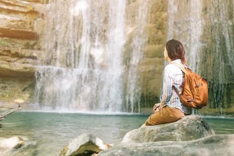 Female backpacker resting in front of waterfall. Stock Photos