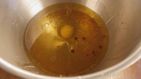 A Female Baker Cracks an Egg and Adds it to a Bowl of Liquid Cake Ingredients 4K Stock Footage 76754825