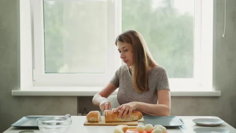 Female Baker Cutting Bread Into Slices in Kitchen Stock Footage 307977029