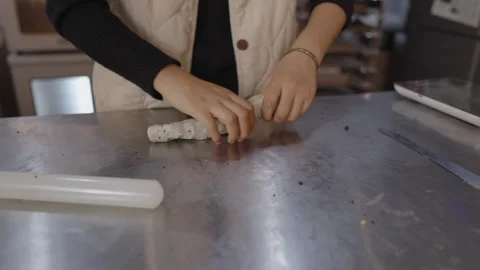 Female baker hands skillfully kneading and rolling a piece of dough on a Видео 328983934