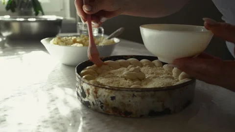 Female baker with light skin using a pink brush to apply glaze on a round cake Vídeo Stock 332736912