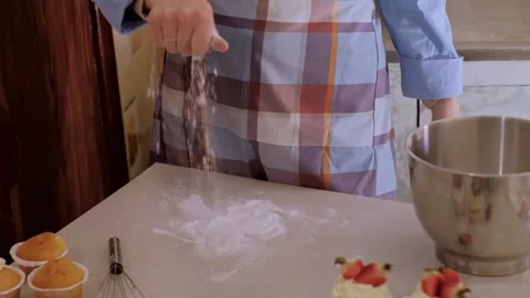 A female baker prepares cupcake batter, sprinkling flour on the table. Home-bake Stock Footage 268247115