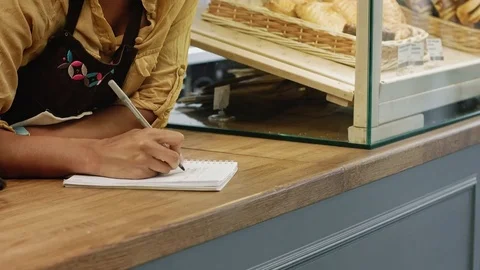 Female baker writing in the notebook while working at her store Video stock 77178519