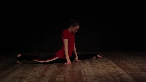 Female ballet dancer warming up in studio on black background 動画素材 104812069