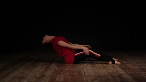 Female ballet dancer warming up in studio on black background 動画素材 104812117