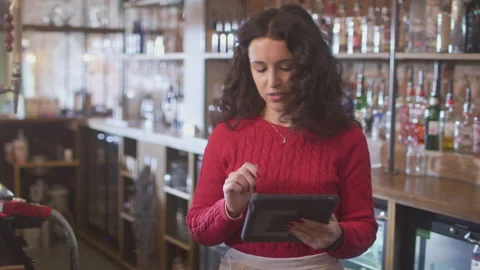 Female Bar Worker Standing Behind Counter Checking Stock Using Digital Tablet Video stock 147663034