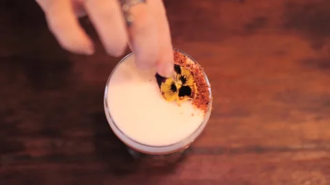 Female Bartender Adding Final Touch with Flower Garnish to Colorful Cocktail 스톡 동영상 305022002