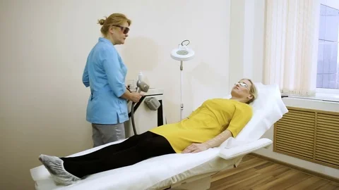 The female beautician doing laser hair removal on the hand of a young woman. HD Stock Footage