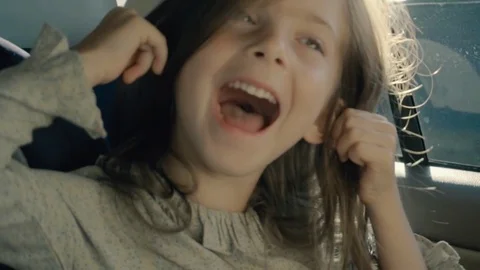 Female beautiful child making faces and having fun while sitting in the in a car Stock Footage 81056837