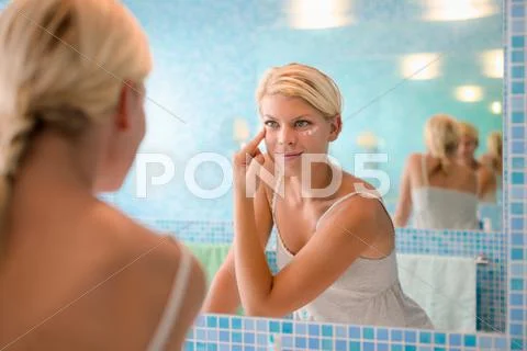 Female beauty, young woman applying lotion on face at home Stock Photos