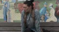 Female on a bench puts coat and scarf on HD Footage