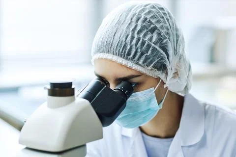 Female bio engineer looking in microscope working in scientific laboratory Stock Photos