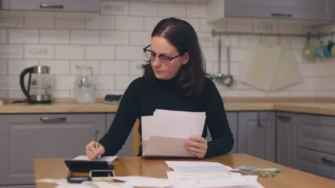 Female in black sit kitchen table look through paper documents sorting papers Video stock 219411560