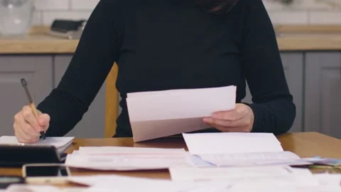 Female in black sit kitchen table look through paper documents sorting papers Stock Footage 229580709