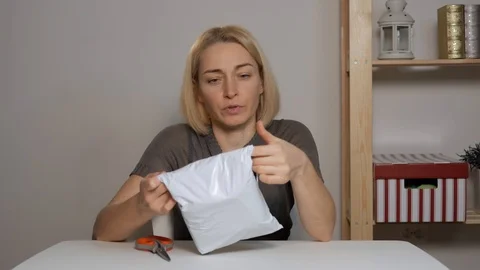 Female blogger sitting at a table studying a purchase with the online store. Stock Footage 122572953