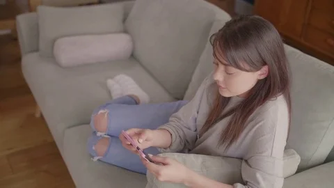 Female blogger using smartphone on sofa at home Stock Footage 79658755