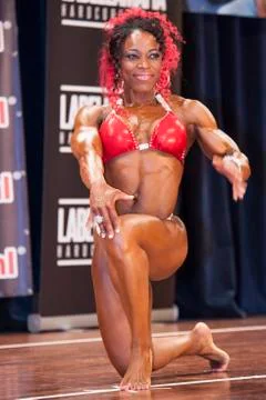 Female bodybuilder in red bikini posing on stage Stock Photos