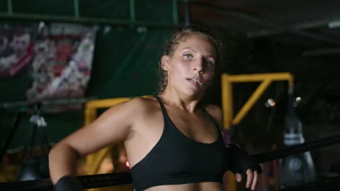 Female boxer Leaning against the ring ropes after fight to catch breath Stock Footage 239862039
