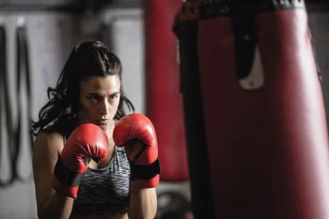 Female boxer practicing boxing with punching bag Stock Photos