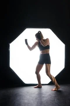 Female boxer training in the dark ring. Slow motion. Silhouette. Boxing concept Stock Photos