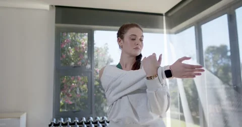 Female bringing right arm across chest, holding at home gym, warming up before Stock Footage 343889484
