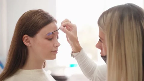 A female brow designer is styling, combing the client's eyebrow. Stock Footage 144639596